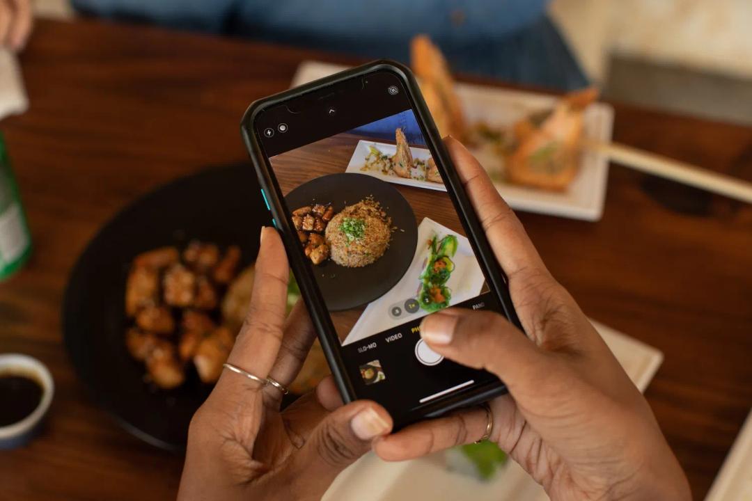Mujer toma la foto de su plato que disfruta de La Plaza en Ciudad del Saber