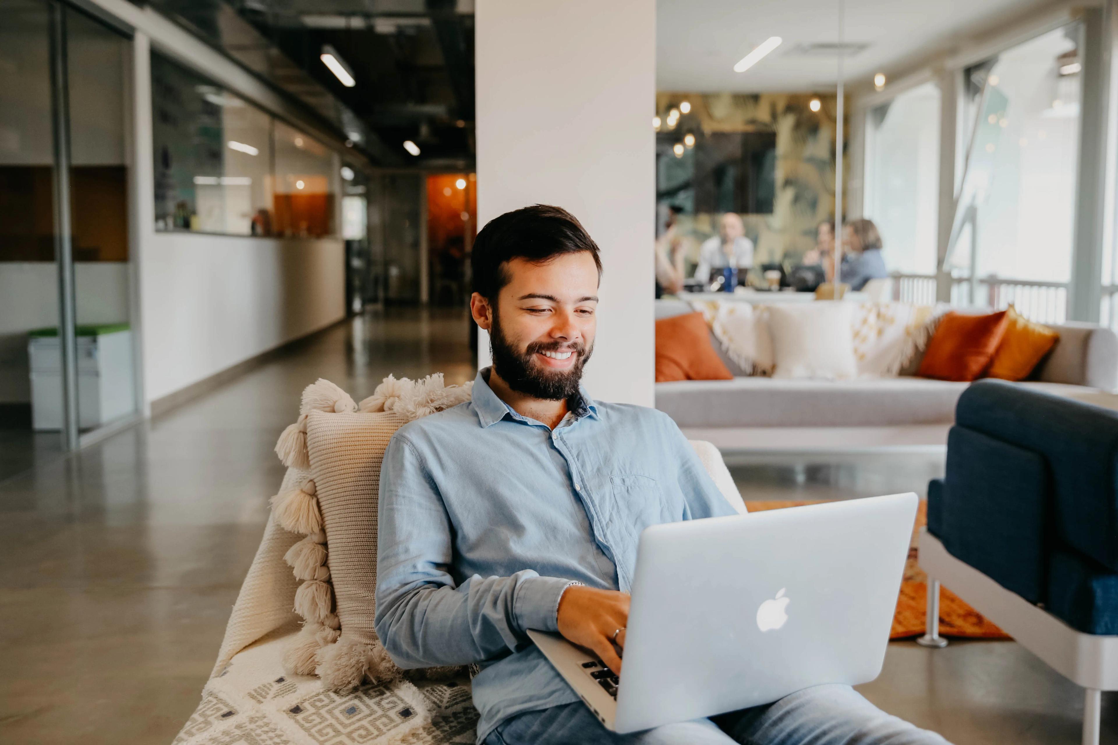 Hombre sentado en una sala mientras sostiene en su piernas un computador