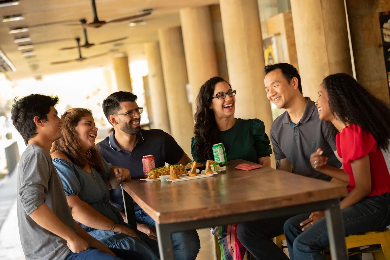 Personas reunidas en una mesa comparten comida y bebidas