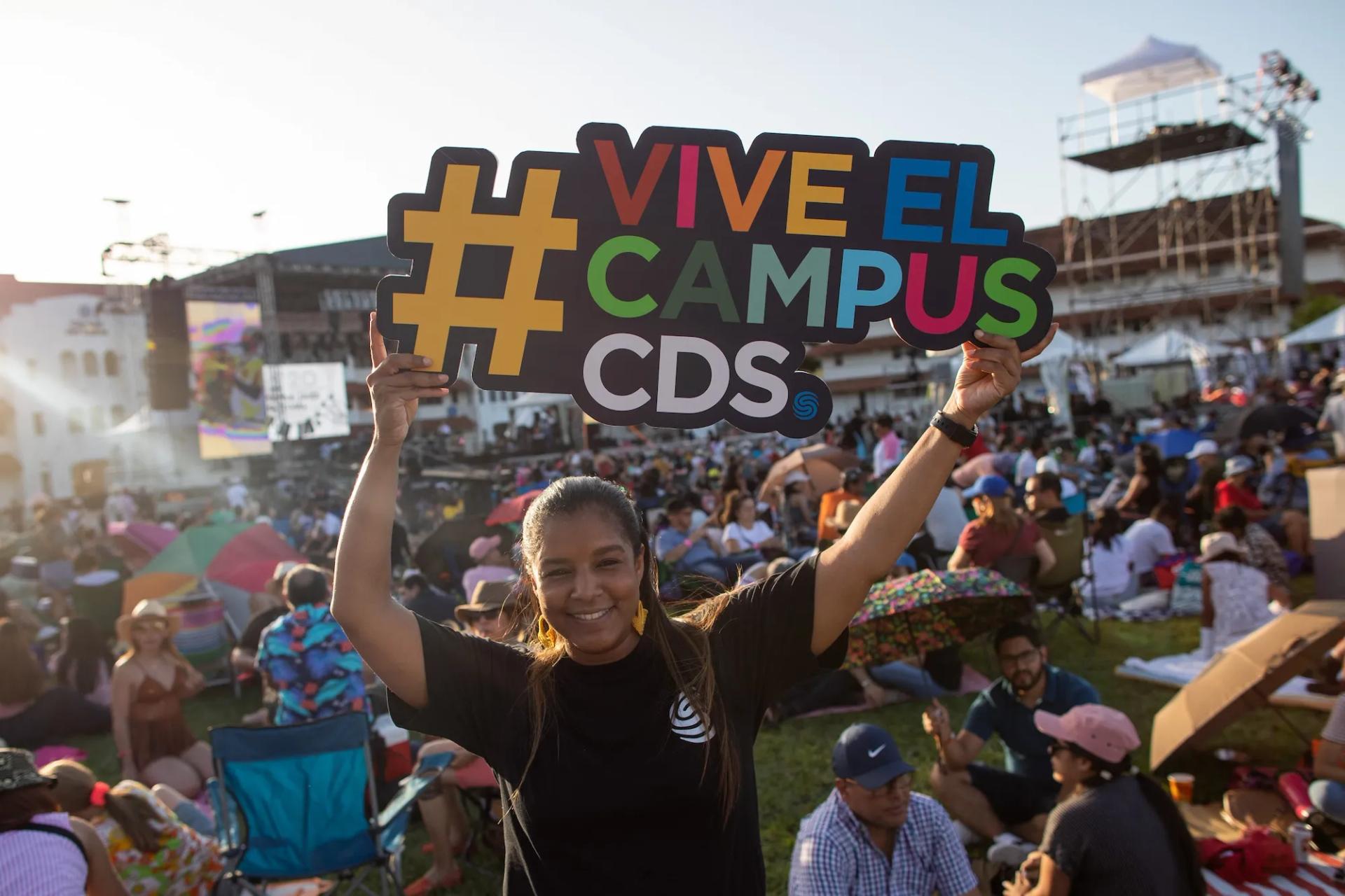 Mujer en medio d eun evento sostiene un cartel de vive el campus Ciudad del Saber