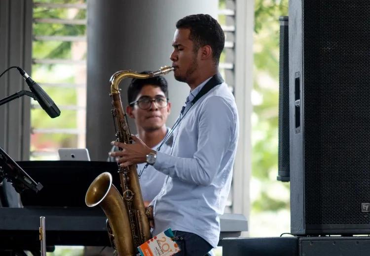 Joven en medio del bazar de Ciudad del Saber toca un saxofón